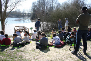 Zoom sur des élèves de primaire assis en face d'un étang