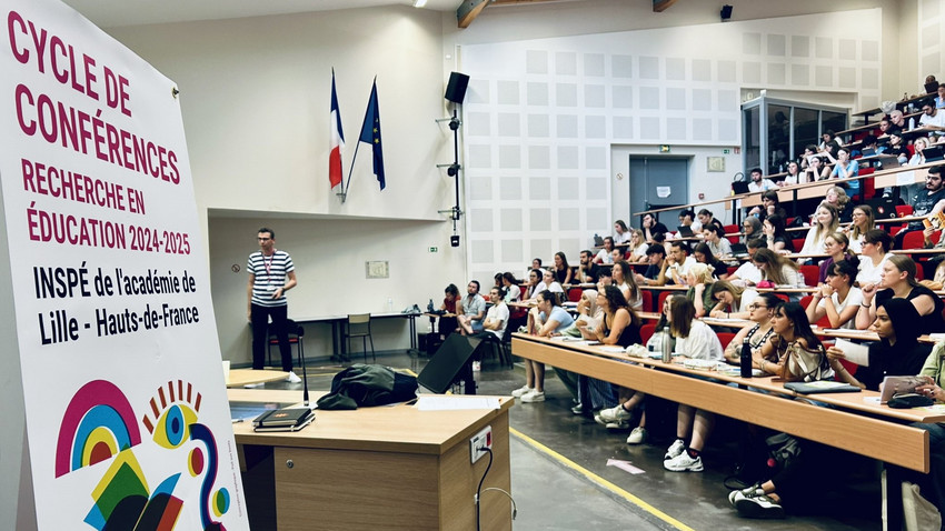 Zoom sur un amphithéâtre plein lors d'une conférence