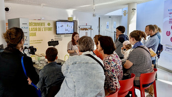 Zoom sur un groupe d'adultes écoute la présentation d'une doctorante sur le plaisir de l'effort physique