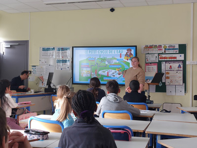 Zoom sur une doctorante qui présente son sujet de recherche à une classe de primaire